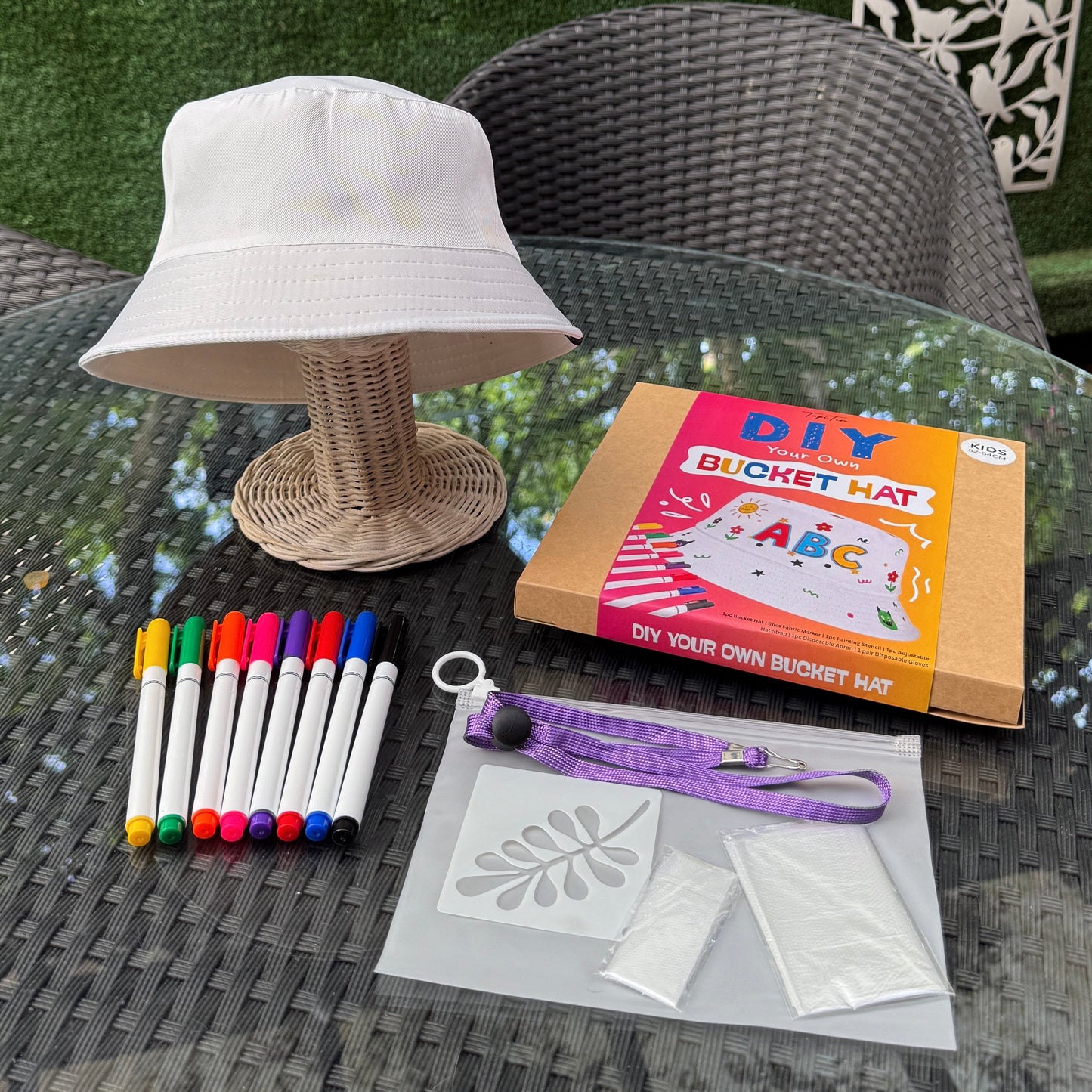 DIY bucket hat kit with materials on a glass table outdoors